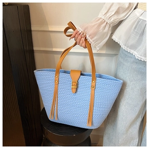 Dettaglio della borsa tote intrecciata blu con cinturini in pelle marrone e fibbia dorata