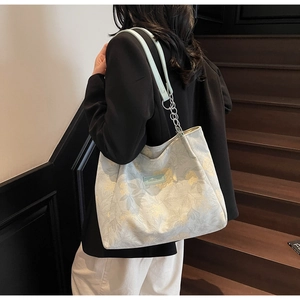 Close-up of light blue floral tote bag with Sakura Diary label and chain shoulder strap