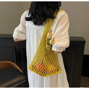 Detailed texture of yellow hand-woven hollow bucket bag on a white lace dress