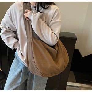 Sac bandoulière marron en nylon porté par un mannequin dans un décor minimaliste