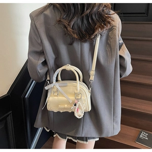 Creamy white bowling bag with bow and lace detail worn as a stylish crossbody bag