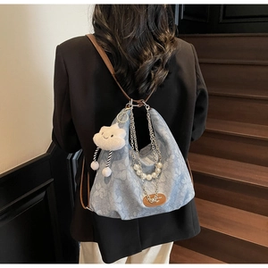 Détail du sac cabas en denim bleu clair avec chaîne perlée et pendentif nuage