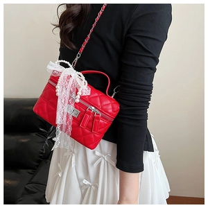 Détail du sac matelassé rouge avec bordure en perles et détails en dentelle blanche