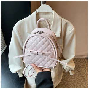 Détail du mini sac à dos rose matelassé avec nœud élégant et zips argentés