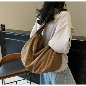 Détail du sac bandoulière en nylon marron foncé montrant sa texture et sa fermeture