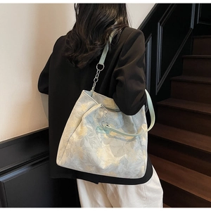 Detailed view of floral canvas tote bag with green leather strap and silver chain detail