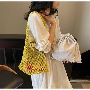 Close-up of bright yellow woven bucket bag with beige drawstring inner pouch and knit texture