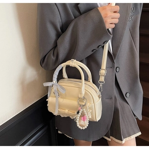 Détail du sac crème en cuir PU avec nœud, bordure en dentelle et breloque en perle