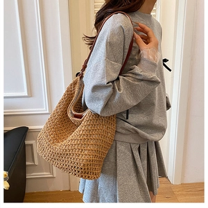 Detail of hand-woven straw shoulder bag with durable dark brown leather strap