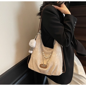 Détail du sac hobo avec texture jacquard florale, chaînes en métal et breloque peluche