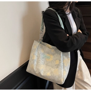 Detail view of floral print tote bag with light green leather strap and silver chain link