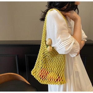 Detail of yellow hand-woven crochet bucket bag with mesh pattern and floral accents