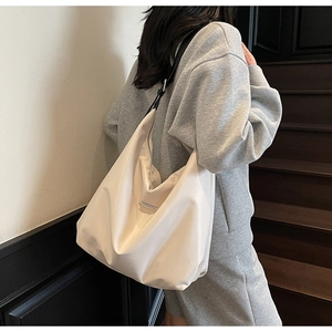 Detail of minimalist cream tote bag with adjustable wide black strap and silver buckle