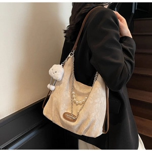 Détail du sac cabas beige avec texture florale, chaîne de perles et breloque nuage
