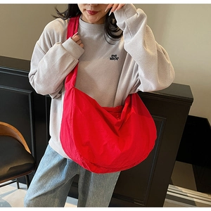 Sac bandoulière en nylon rouge en forme de croissant porté par un mannequin en mode décontracté