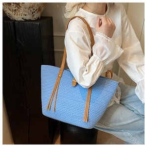 Dettaglio della borsa tote tessuta a mano azzurra con cinturini in pelle kaki e frange
