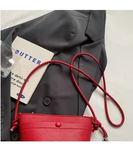 Détail du sac bandoulière en cuir grainé rouge avec nœud décoratif et fine bandoulière