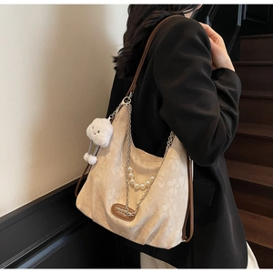 Détail du sac cabas jacquard beige avec chaîne perlée, breloque et anses en cuir