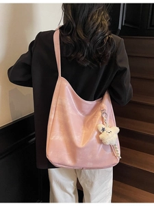 Sac à bandoulière rose en similicuir avec charm ours porté sur un escalier en bois