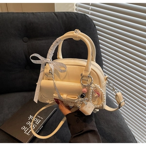 Detail of cream bowling bag featuring bow lace trim and trendy charms on handle