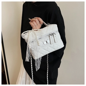 Détail d'un sac matelassé blanc avec nœud en perles et bandoulière chaîne argentée