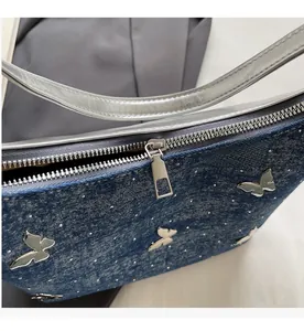Detail of smooth silver zipper and blue denim texture with crystal butterfly charm