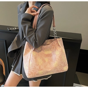 Detail of pink floral tote bag with leather nameplate and metal chain shoulder straps