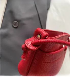 Détail d'un sac à main rouge en cuir grainé avec rivet métallique argenté et cordon chic