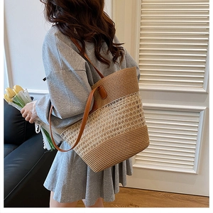 Dettaglio di borsa tote in paglia con manici in pelle marrone indossata da modella