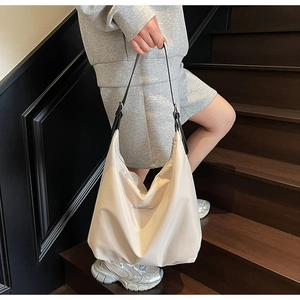 Detail of minimalist cream crossbody bag featuring nylon fabric and silver buckle accent