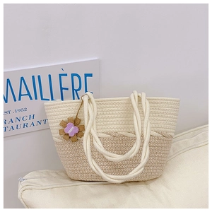 Détail d'un sac cabas en paille bicolore avec poignées en coton et charm floral