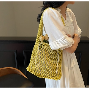Close-up of a bright yellow hand-woven hollow mesh bucket bag with a beige drawstring liner