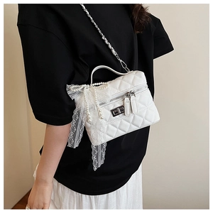 Détail du sac bandoulière matelassé blanc avec nœud en dentelle et perles décoratives