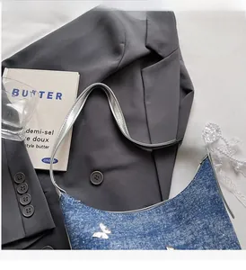 Close-up of blue denim Y2K underarm bag with silver butterfly hardware details