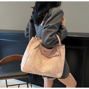 Detail view of pink floral tote bag with leather strap and silver chain on model