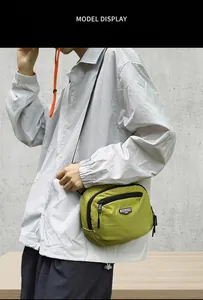 Dettaglio della borsa a tracolla in nylon verde senape con tasche a zip e logo