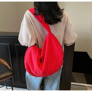 Sac bandoulière en nylon rouge porté par un mannequin dans un café chic