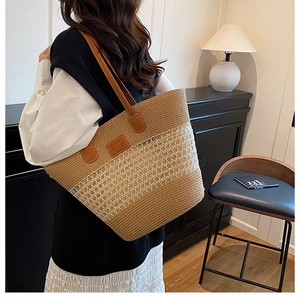 Dettaglio della borsa tote in paglia intrecciata con tracolla in pelle e logo