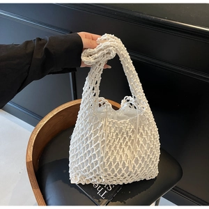Detail of white hand-woven bucket bag featuring a cotton rope mesh and canvas drawstring liner