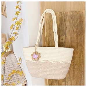 Détail du sac cabas en paille tressée avec anses en corde et breloque fleur mauve