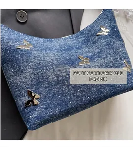 Detail of blue denim shoulder bag featuring silver metal butterfly and rhinestone studs