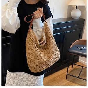 Detail of woven straw hobo bag showing khaki texture and brown leather shoulder strap
