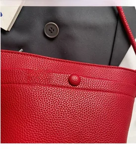 Détail du sac à main en cuir grainé rouge avec coutures précises et fermeture à bouton