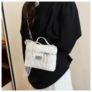 Détail d'un sac bandoulière blanc matelassé avec nœud en dentelle perlée et fermoir argent