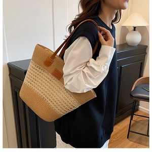 Dettaglio della borsa tote in paglia intrecciata con cinturini in pelle marrone e toppa