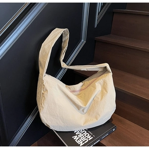 Détail du sac croissant en nylon beige avec texture plissée et fermeture zippée