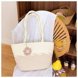 Détail du sac cabas tissé avec pendentif fleur marron et poignées nouées sur une chaise