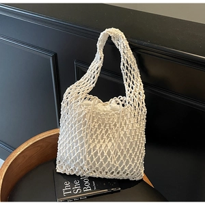 Detail shot of the white woven macramé bucket bag featuring a drawstring fabric inner pouch