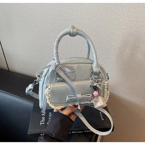Detail of light blue bow bag with lace trim, pearl charm, and plaid scarf handle