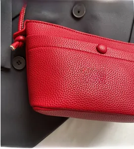 Gros plan du sac bandoulière rouge en cuir grainé avec bouton-pression et couture fine